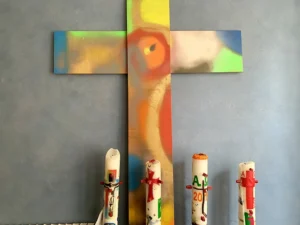 Ein buntes Kreuz mit vier bunten Kerzen