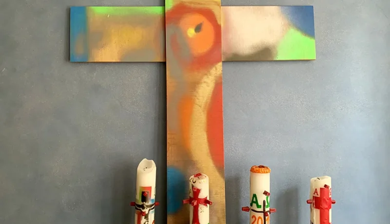 Ein buntes Kreuz mit vier bunten Kerzen